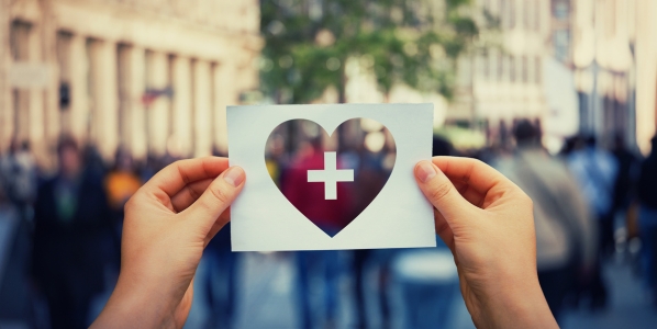 Person holding a heart with a plus sign paper
