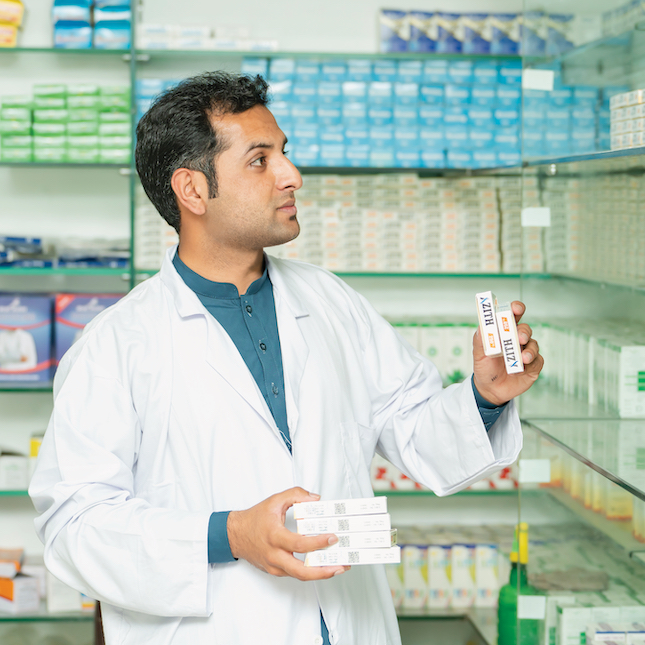 man in lab coat stocking medicine in a pharmacy