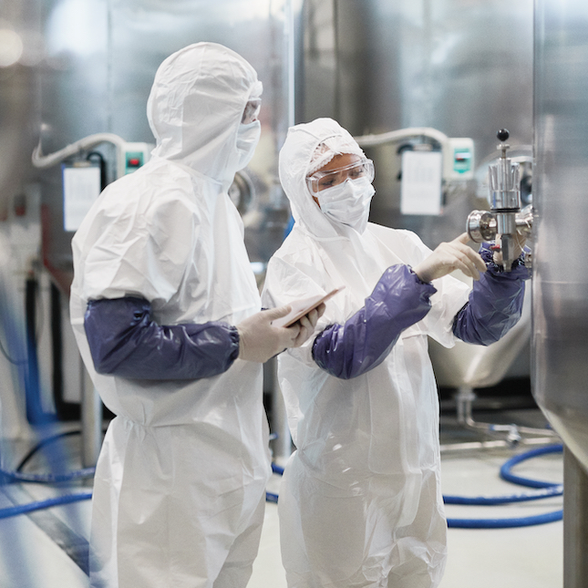 People in protective suits and masks working in a factory