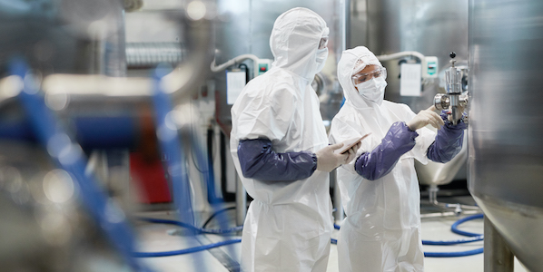 side view portrait two workers wearing protective suits while using equipment modern chemical plant